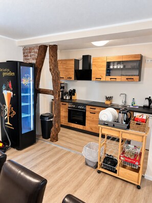 A modern kitchen with wooden cabinets, a black refrigerator, and a coffee machine. - Comfortable and versatile room-perfect for relaxation, work and exchange (Winterberg)