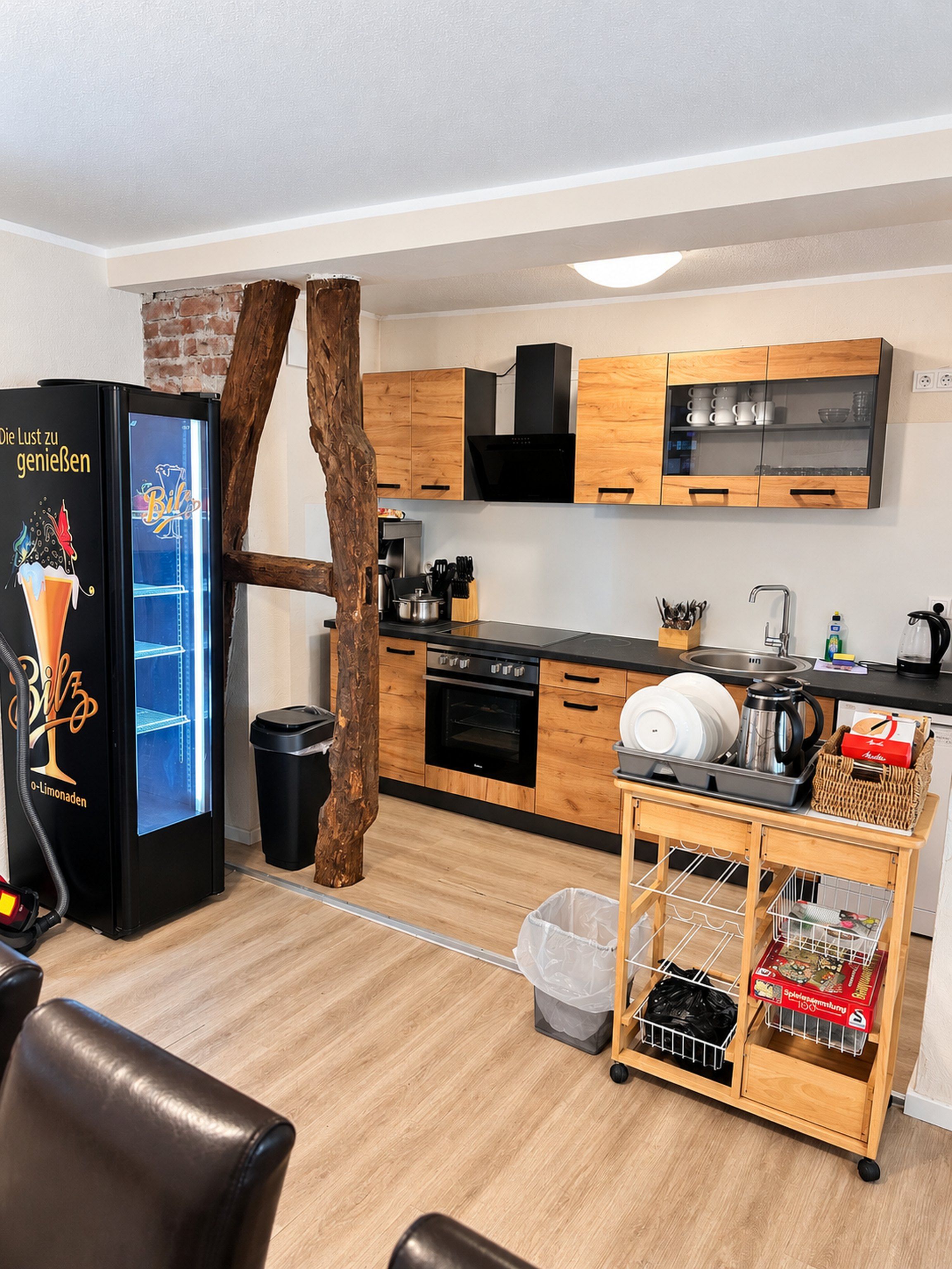 A modern kitchen with wooden cabinets, a black refrigerator, and a coffee machine.