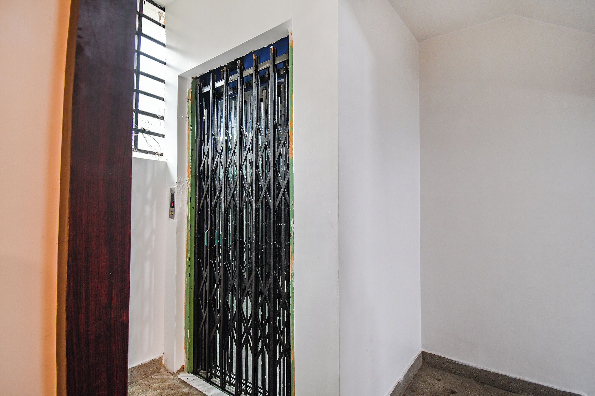 A narrow hallway with a white door featuring a black metal security gate.