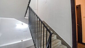 A staircase with a black metal railing, a white wall, and a wooden door. - Hotel Green Leaf (Kolkata)