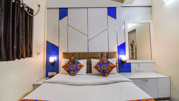 A hotel room with a bed, bedside lamps, a dresser, and a mirror. - Hotel Green Leaf (Kolkata)