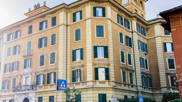 Kulmassa sijaitseva rakennus, jossa on useita ikkunoita ja jalankulkijoiden suojatien opaste.