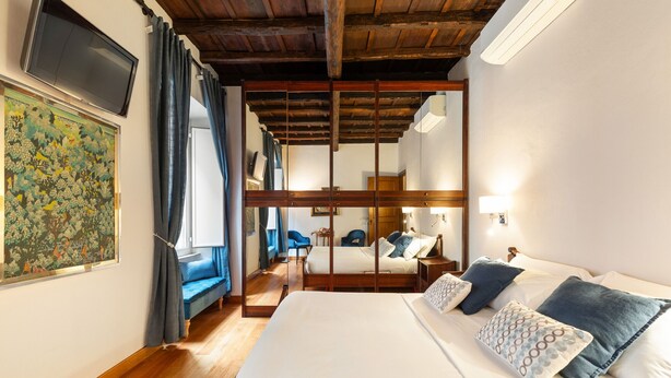 Een hotelkamer met een groot bed, een houten plafond, een televisie en een schilderij aan de muur.