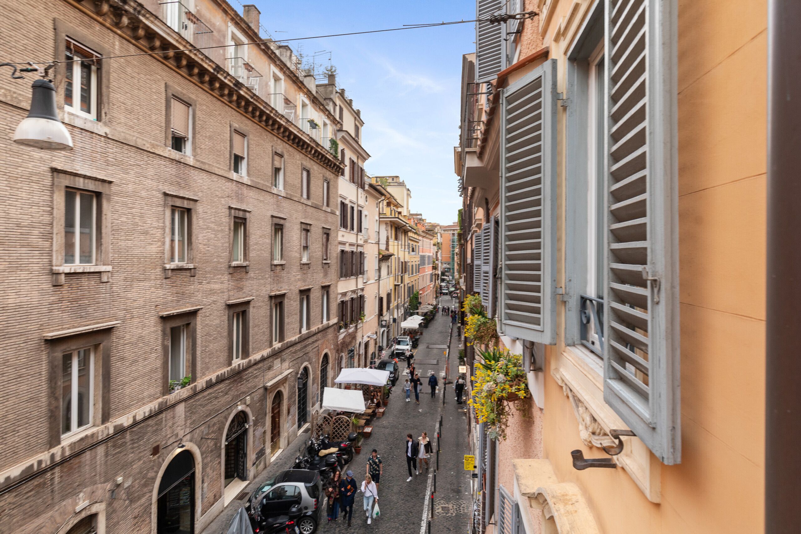 Un vicolo stretto fiancheggiato da edifici a più piani, alcuni con balconi e tende da sole visibili, che suggerisce un contesto urbano storico.