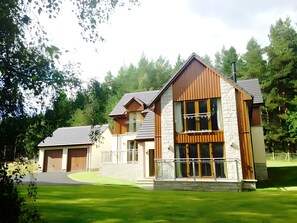 A modern two-story house with a stone facade, large windows, and a garage. - Carn Mhor Lodge, Aviemore (Aviemore)