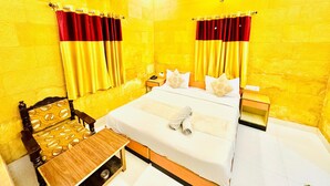 A hotel room with a bed, bedside tables, a chair, and an air conditioning unit. - Hotel Amar Haveli (Jaisalmer)
