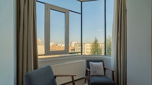 Una habitación con dos sillas, una mesa y vistas a edificios a través de una ventana.