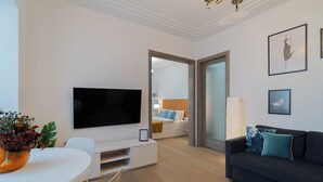 Una sala de estar moderna con un televisor de pantalla plana, un sofá, una mesa de comedor y una planta en maceta.