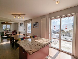 A spacious kitchen with a granite countertop, a dining area with a table and chairs, and large sliding glass doors leading to a balcony.