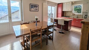 A modern kitchen with red cabinets, a marble countertop, and a view of the outdoors.
