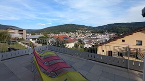 A terrace with a view of a town and mountains.