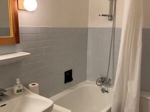 A bathroom with a white sink, a mirror, a shower with a curtain, and a toilet. - Charming studio in the heart of Moriond 1650, perfect for 2 adults and 1 child (Courchevel)