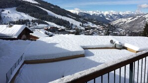 A snow-covered mountain village with wooden buildings and a clear view of distant snow-capped mountains.