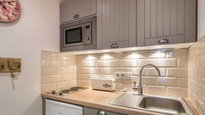 A compact kitchen with a microwave, toaster, sink, and a dishwasher.