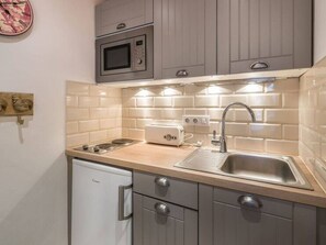 A compact kitchen with a microwave, toaster, sink, and a dishwasher. - Charming studio in the heart of Moriond 1650, perfect for 2 adults and 1 child (Courchevel)