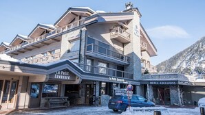 A hotel with a modern architectural design, featuring balconies and a stone facade.