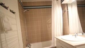 A bathroom with a bathtub, a sink, and a mirror.