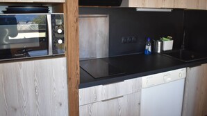 Een kleine keuken met een magnetron, een fornuis en een vaatwasser.