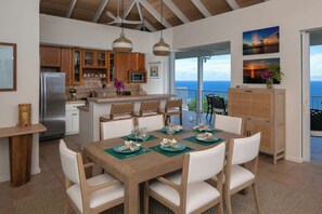 A spacious kitchen with wooden cabinets, a stainless steel refrigerator, and a dining area with a wooden table set for four.