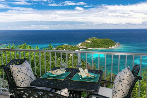 A table set with a view of the ocean and a small island.
