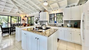 A spacious kitchen with a large island, white cabinetry, and a ceiling fan. - Oceanfront Villa-Private Pool-Panoramic Views -Sleeps 12 (St. Thomas)