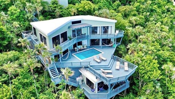 A multi-level house with a pool, surrounded by dense tropical vegetation. - Oceanfront Villa-Private Pool-Panoramic Views -Sleeps 12 (St. Thomas)