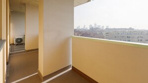 Un balcon avec vue sur la ville, un sol carrelé et un plafond avec des poutres apparentes.