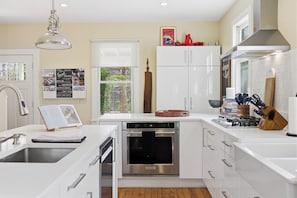 A modern kitchen with white cabinetry, a built-in oven, and a window with a view of greenery.