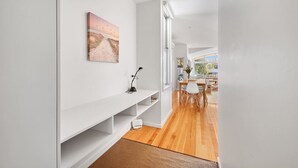 Un interior moderno con una pared blanca, un cuadro, una consola blanca y suelo de madera.