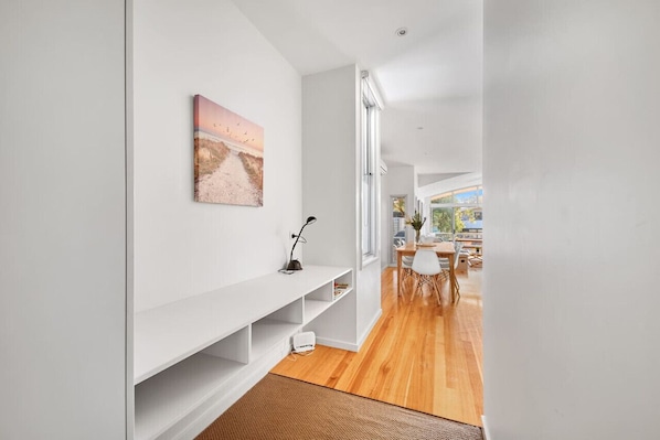 A modern interior with a white wall, a painting, a white console table, and a wooden floor.