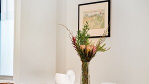 Un comedor con una mesa de madera, sillas blancas y un florero con flores.