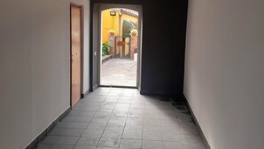 A hallway with a tiled floor leading to an outdoor area with a gate and plants.