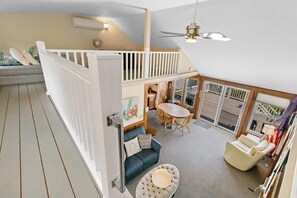 Amplia habitación estilo loft con techo alto, balcón, zona de comedor y espacio de estar con sofá y sillones.
