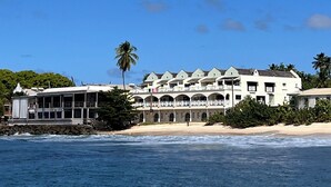 A beachfront hotel with multiple balconies, a pool, and a view of the ocean.