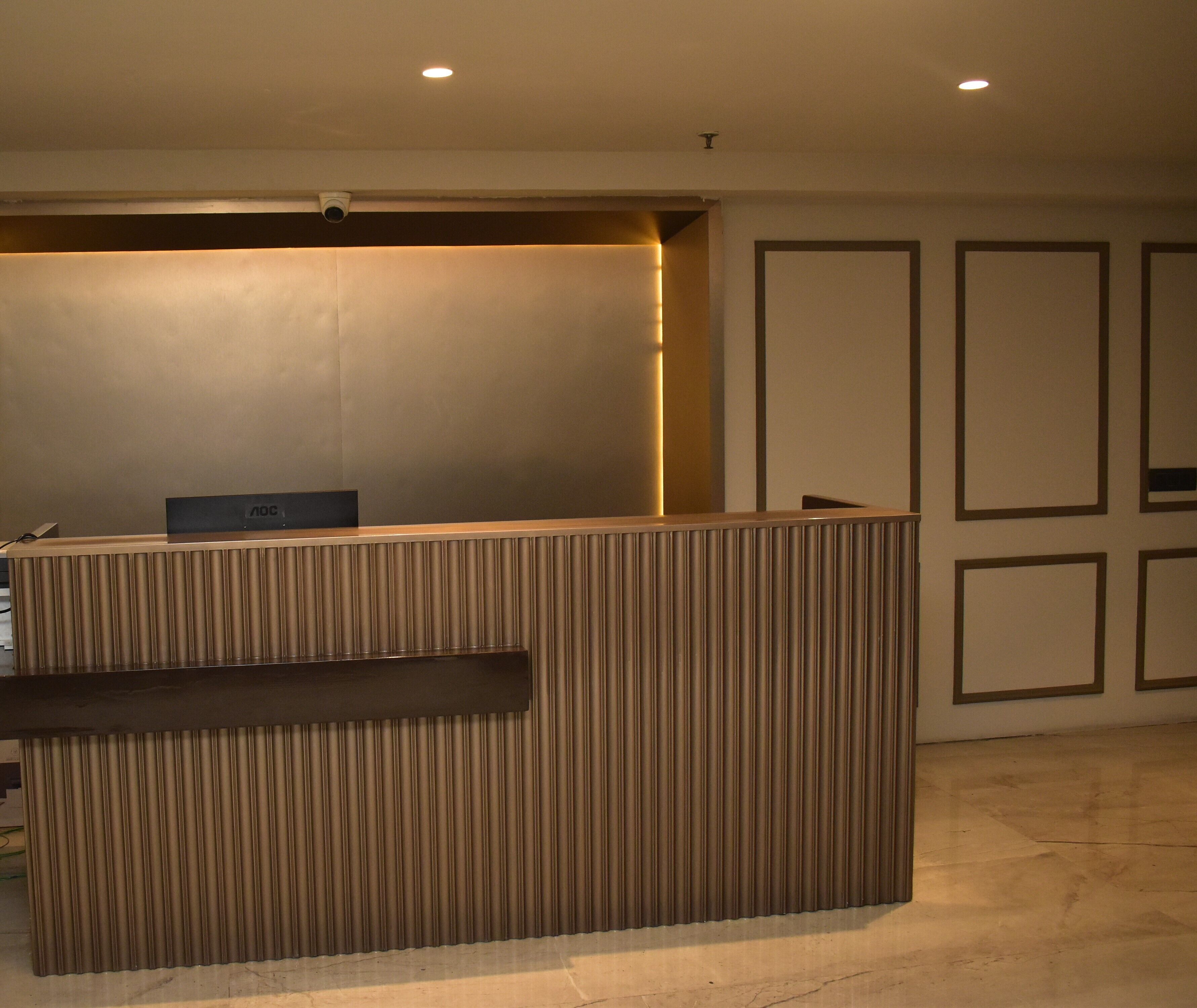A reception desk with a modern design, a flat-screen TV, and a security camera above it.