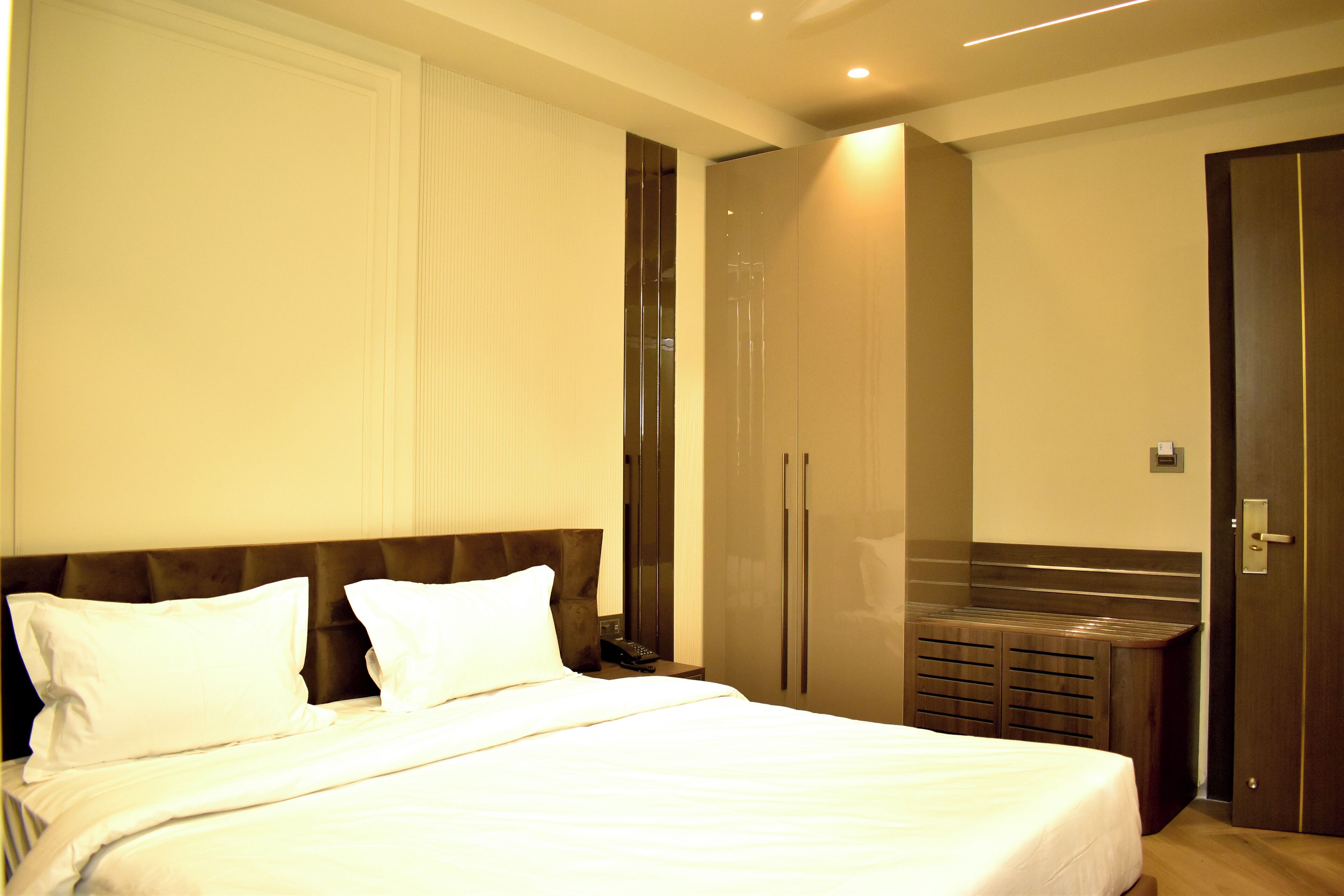 A hotel room with a large bed, a wardrobe, and a small seating area.