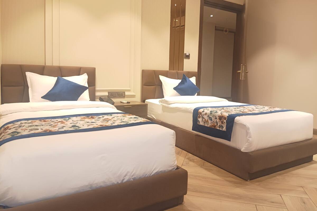 A hotel room with two beds, each with a headboard, bedside tables, and a telephone.