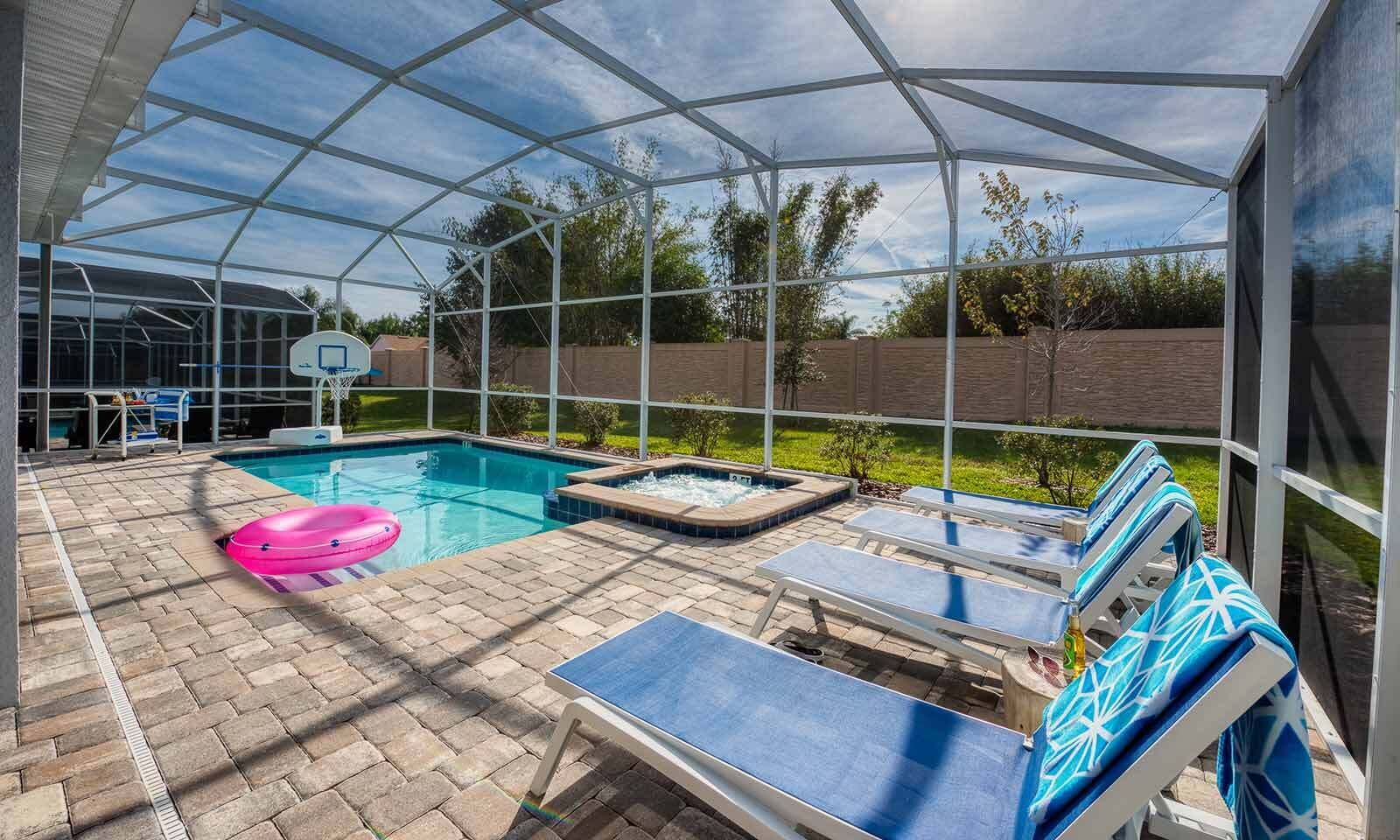 A covered outdoor swimming pool with lounge chairs and a hot tub.