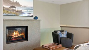 A living room with a fireplace, a sofa, a chair, and a rug. - Oceanview Townhome Steps from Iconic Windansea Beach (San Diego)