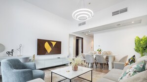 Een moderne woonkamer met een bank, salontafel en een eethoek met stoelen en een tafel.