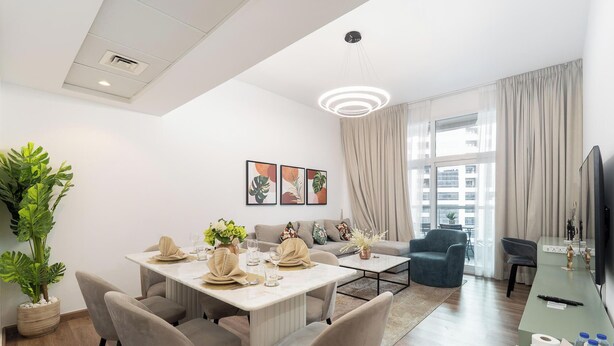 Een moderne woonkamer met een eethoek, grote ramen en een flatscreen televisie.