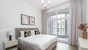 Een moderne hotelkamer met een groot bed, een nachtkastje, een lamp, een kroonluchter en een groot raam met gordijnen.