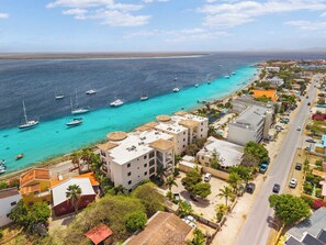 Une ville côtière avec des bâtiments le long de la plage, une route et des bateaux sur l’eau.