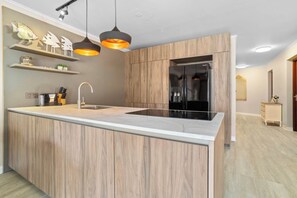 A modern kitchen with a central island, built-in appliances, and pendant lighting. - Elegancia Ocean View with Cooling Pool (Kralendijk)