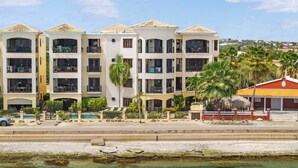 Un hotel de diverses plantes amb balcons, una piscina i vista al mar.