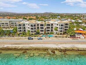 A multi-story hotel with balconies, a swimming pool, and a view of the surrounding residential area. - Elegancia Ocean View with Cooling Pool (Kralendijk)