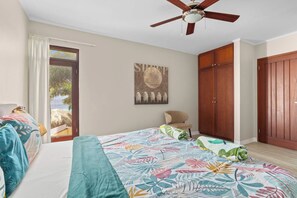 A bedroom with a bed, a ceiling fan, a chair, a wardrobe, and a window with a view of the outdoors. - Elegancia Ocean View with Cooling Pool (Kralendijk)