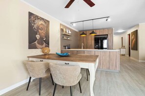Une cuisine moderne dotée d’un îlot central, de luminaires suspendus et d’un coin repas avec deux chaises et une table.
