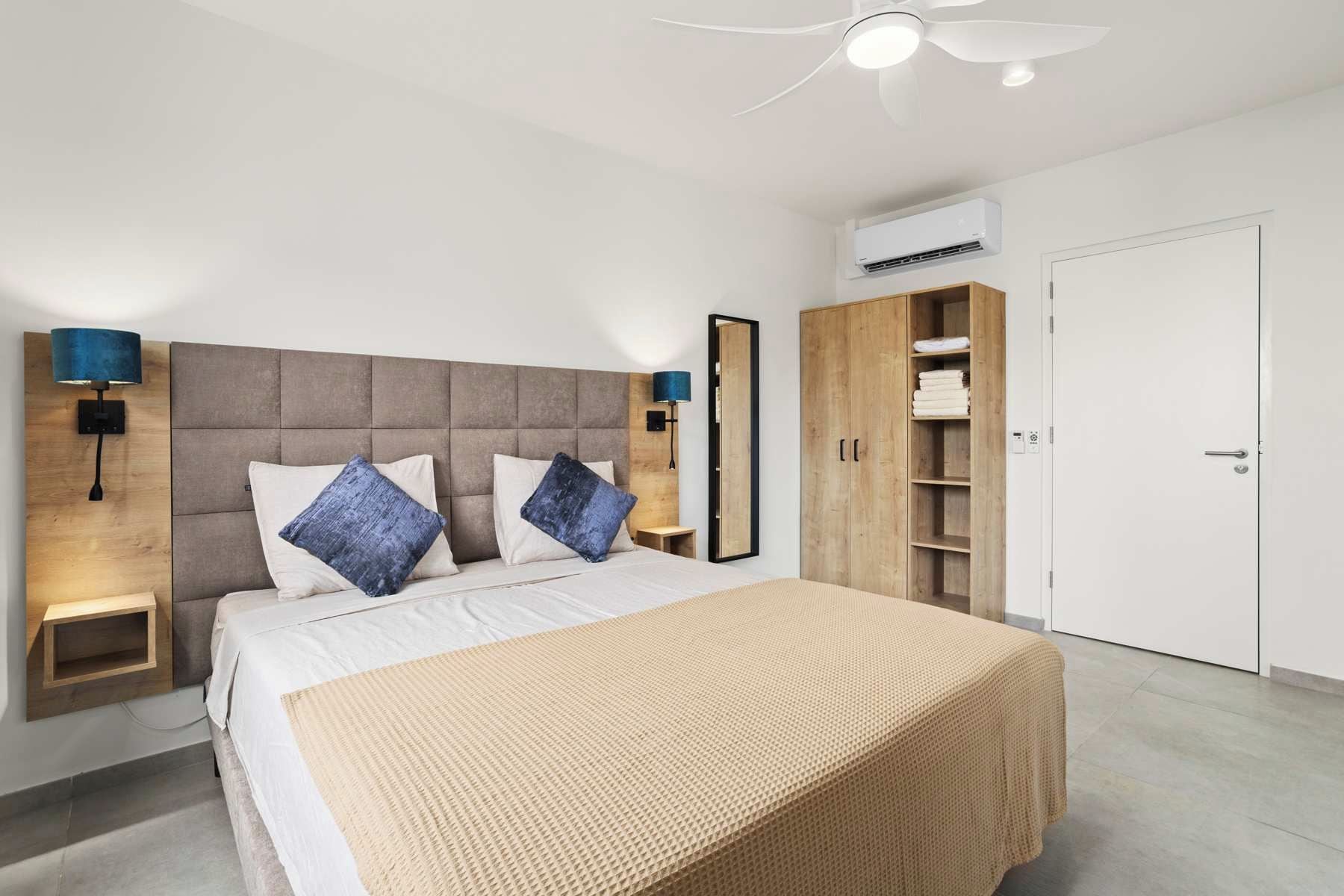 Une chambre moderne comprenant un lit, des lampes de chevet, une armoire et un appareil de climatisation.