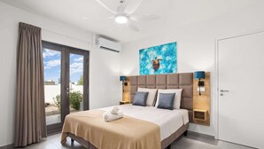 A hotel room with a bed, a ceiling fan, a painting of a sea turtle, and a view through the glass door. - Bonaire Beach Apartments 2 with a palm garden, a refreshing shared pool and a private sitting area (Kralendijk)
